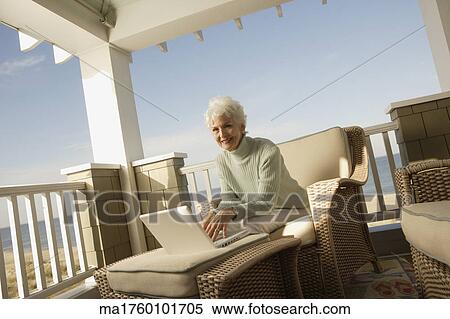 Senior woman using a laptop on the porch View Large Photo Image Stock Photography - Senior woman using a laptop on the porch. Fotosearch