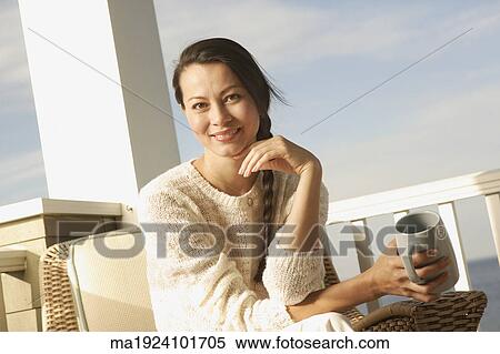 Stock Photography - Woman having a cup of coffee on the porch. Fotosearch