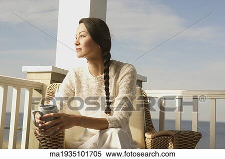 Stock Photography - Woman having a cup of coffee on the porch. Fotosearch