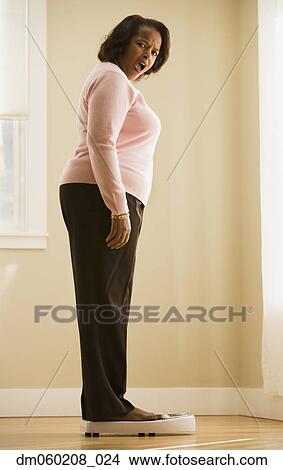 Picture - Woman weighing herself. Fotosearch