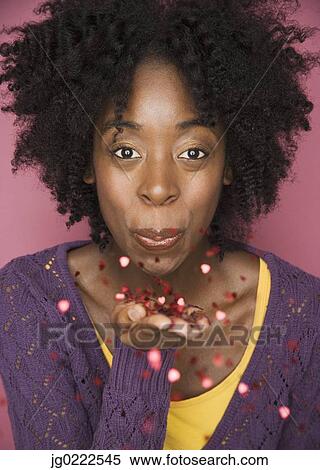Stock Photography - Young woman blowing confetti. Fotosearch
