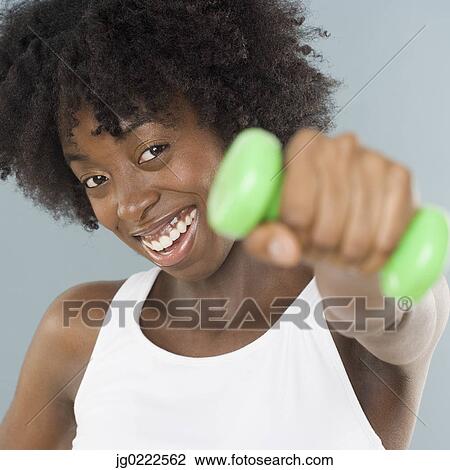 Stock Image - Young woman lifting weights. Fotosearch