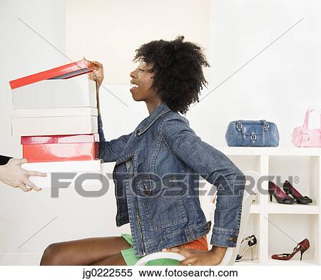 Stock Photography - Young woman looking in shoe boxes. Fotosearch