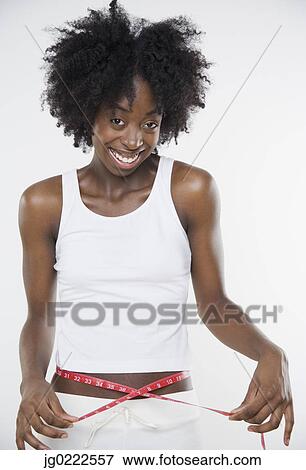 Stock Photo - Young woman measuring her waist. Fotosearch