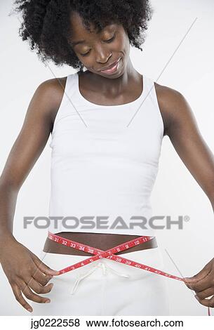 Young woman measuring her waist View Large Photo Image Stock Photo - Young woman measuring her waist. Fotosearch