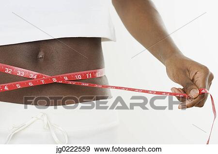 Young woman measuring her waist View Large Photo Image Stock Photo - Young woman measuring her waist. Fotosearch