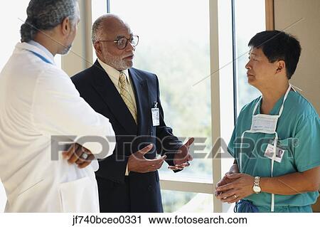 African businessman talking to male Asian surgeon and male African doctor View Large Photo Image Stock Image - African businessman talking to male Asian surgeon and male African doctor. Fotosearch