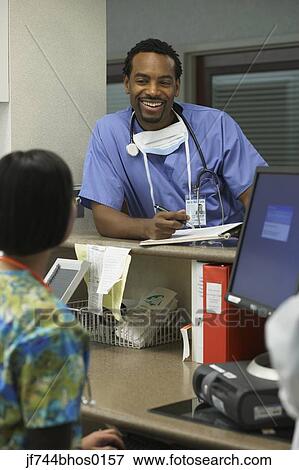 Stock Photo - African male surgeon talking to nurse, Bethesda, Maryland, United States. Fotosearch