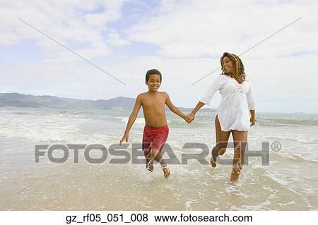 Stock Photo - African mother and son running in the surf, Florianopolis, Brazil. Fotosearch