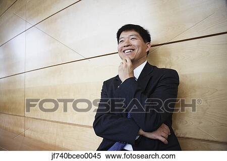 Asian businessman leaning on the wall smiling View Large Photo Image Stock Photography - Asian businessman leaning on the wall smiling. Fotosearch