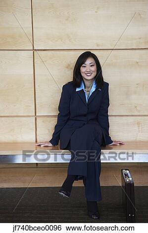 Asian businesswoman sitting on bench indoors View Large Photo Image Stock Photograph - Asian businesswoman sitting on bench indoors. Fotosearch