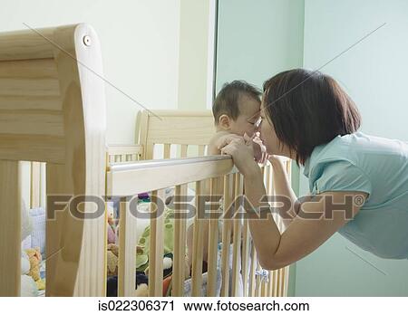 Asian mother and baby touching noses over crib View Large Photo Image Stock Image - Asian mother and baby touching noses over crib. Fotosearch