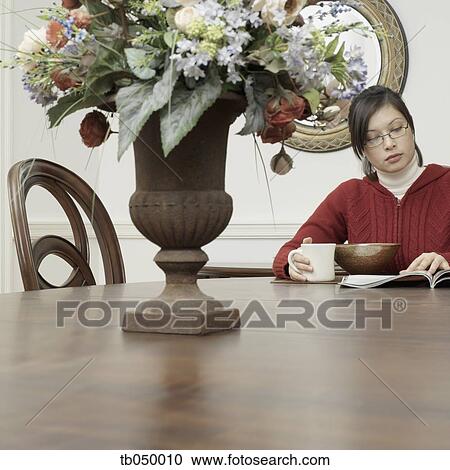 Asian woman eating and reading at dining table View Large Photo Image Stock Image - Asian woman eating and reading at dining table. Fotosearch