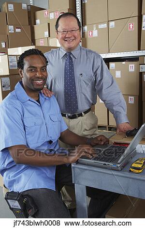 Businessman and co-worker in shipping department View Large Photo Image Stock Photo - Businessman and co-worker in shipping department. Fotosearch