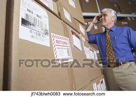 Businessman in warehouse looking at returned packages View Large Photo Image Stock Image - Businessman in warehouse looking at returned packages. Fotosearch