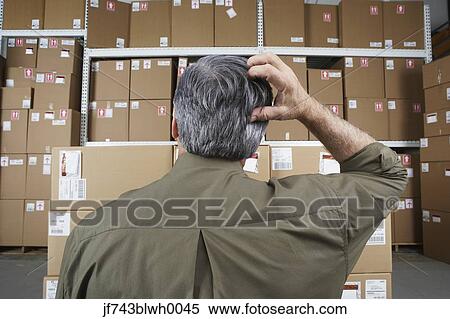 Businessman in warehouse scratching his head View Large Photo Image Stock Photography - Businessman in warehouse scratching his head. Fotosearch