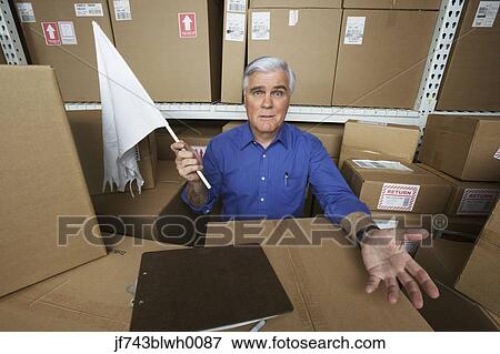 Businessman in warehouse waving white flag View Large Photo Image Stock Photo - Businessman in warehouse waving white flag. Fotosearch