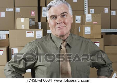 Businessman standing in warehouse View Large Photo Image Picture - Businessman standing in warehouse. Fotosearch
