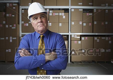 Businessman wearing hard hat in warehouse View Large Photo Image Stock Image - Businessman wearing hard hat in warehouse. Fotosearch