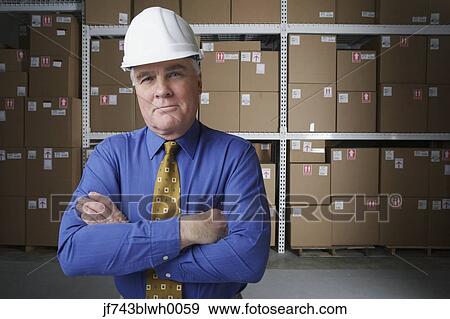 Businessman wearing hard hat in warehouse View Large Photo Image Stock Photo - Businessman wearing hard hat in warehouse. Fotosearch
