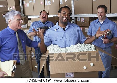 Stock Image - Businessman with male warehouse workers joking around. Fotosearch