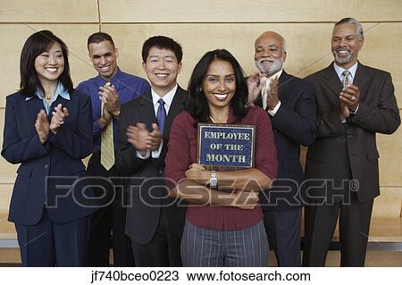 Businesswoman holding Employee of the Month plaque with co-workers applauding View Large Photo Image Stock Image - Businesswoman holding Employee of the Month plaque with co-workers applauding. Fotosearch