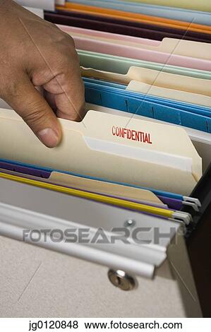 Stock Photo - Close up of African male hand selecting confidential file from drawer. Fotosearch
