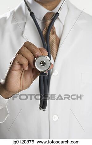 Stock Photograph - Close up of male doctor's hand holding stethoscope. Fotosearch