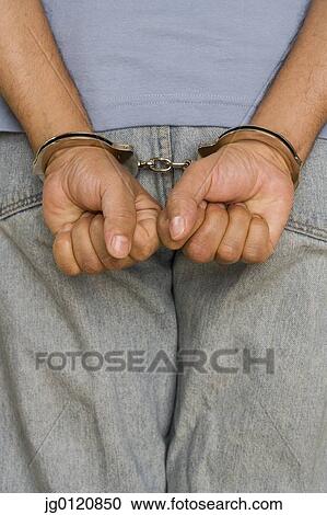 Stock Image - Close up of male hands in handcuffs. Fotosearch