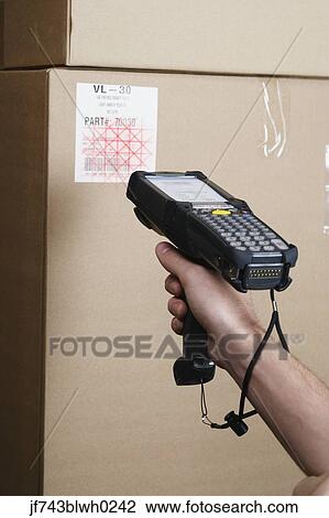 Stock Image - Close up of scanner gun scanning package . Fotosearch