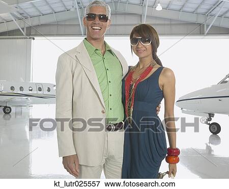 Stock Photo - Couple hugging in airplane hanger, Nobato, California, United States. Fotosearch