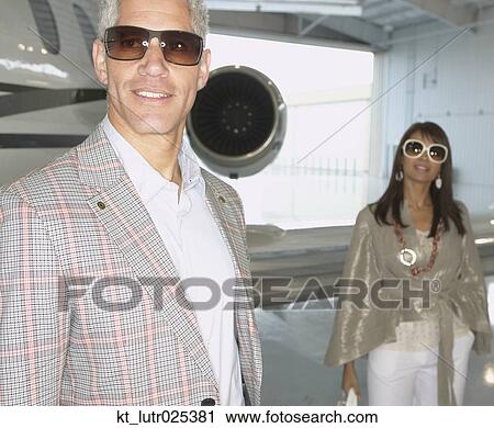 Stock Image - Couple standing in front of airplane in a hanger, Nobato, California, United States. Fotosearch