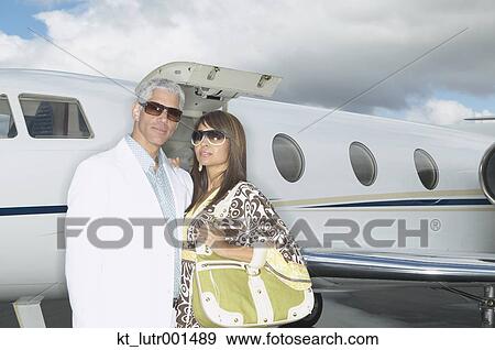 Stock Photo - Couple standing in front of small jet, Nobato, California, United States. Fotosearch