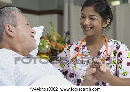 Stock Image - Female nurse holding patient's hand, Bethesda, Maryland, United States. Fotosearch