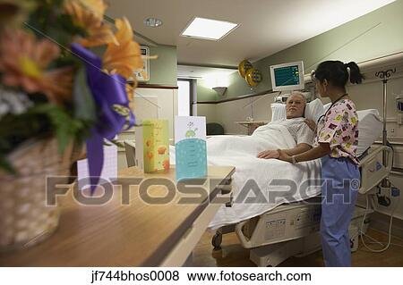Stock Photo - Female nurse with patient in hospital bed, Bethesda, Maryland, United States. Fotosearch