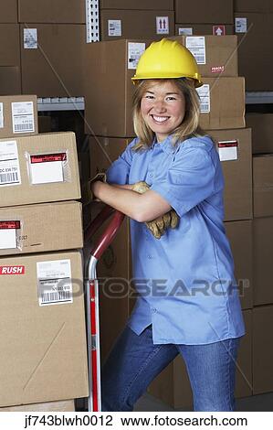 Stock Image - Female warehouse worker with hard hat. Fotosearch
