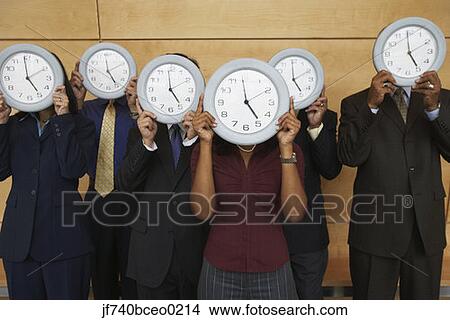 Group of businesspeople holding clocks over their faces View Large Photo Image Picture - Group of businesspeople holding clocks over their faces. Fotosearch