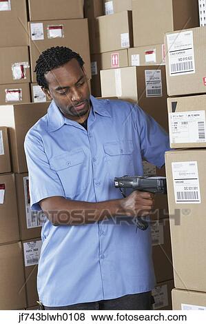 Stock Photo - Male African warehouse worker scanning packages. Fotosearch