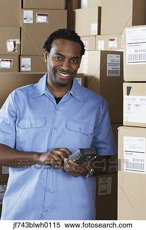 Stock Photography - Male African warehouse worker scanning packages. Fotosearch