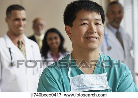 Male Asian surgeon with co-workers in the background View Large Photo Image Stock Photo - Male Asian surgeon with co-workers in the background. Fotosearch