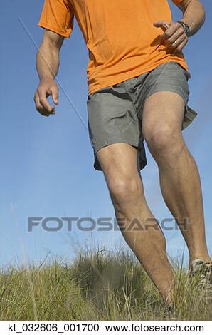 Stock Image - Man walking through grass, California, United States. Fotosearch