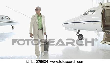 Man walking with suitcase in airplane hanger, Nobato, California, United States View Large Photo Image Picture - Man walking with suitcase in airplane hanger, Nobato, California, United States. Fotosearch