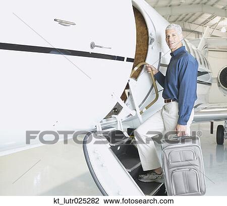 Man with suitcase boarding airplane in hanger, Nobato, California, United States View Large Photo Image Stock Image - Man with suitcase boarding airplane in hanger, Nobato, California, United States. Fotosearch