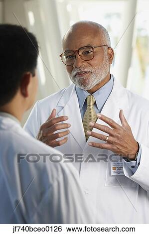 Middle-aged African doctor talking to co-worker View Large Photo Image Stock Photograph - Middle-aged African doctor talking to co-worker. Fotosearch