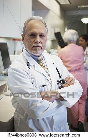 Stock Image - Middle-aged male doctor with arms crossed, Bethesda, Maryland, United States. Fotosearch