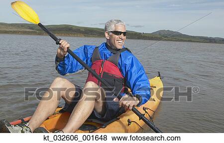 Stock Photo - Middle-aged man rowing a kayak in still water, California, United States. Fotosearch