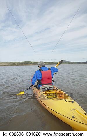 Stock Image - Rear view of person rowing a kayak in still water, California, United States. Fotosearch