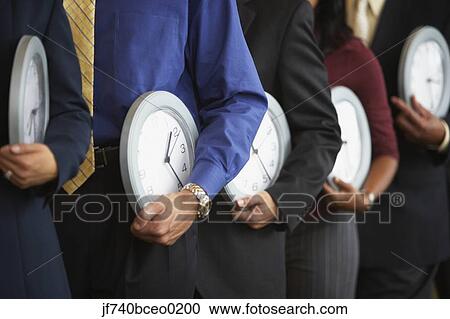 Row of businesspeople holding clocks View Large Photo Image Stock Image - Row of businesspeople holding clocks. Fotosearch