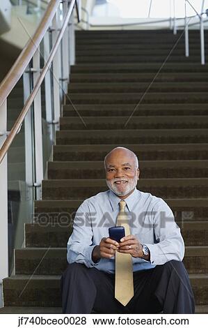 Senior African businessman using electronic organizer on stairs View Large Photo Image Stock Photo - Senior African businessman using electronic organizer on stairs. Fotosearch