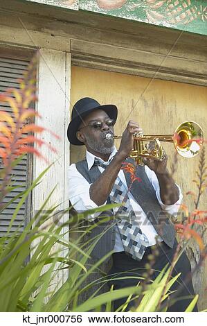 Stock Photograph - Senior African man playing the trumpet while leaning in a doorway, Oakland, California, United States. Fotosearch